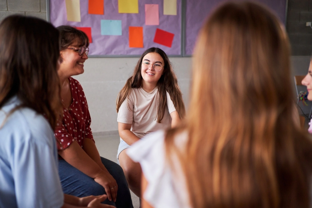 Teenage student girls sharing and talking at support group meeting.