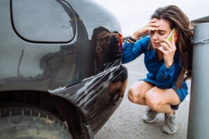 mujer de pie junto a un automóvil rayado después de un accidente