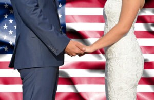 husband and wife holding hands in front of an American flag