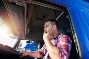 Camionero bostezando mientras conduce. 5 razones por las que necesita un abogado de accidentes de camiones